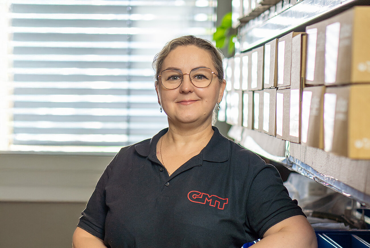 Person im Lagerbereich vor Regalen mit Arbeits- und Sicherheitsausstattung.