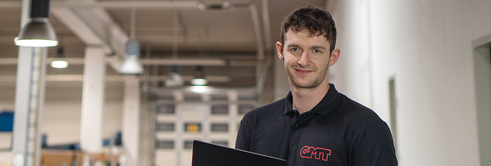 Person mit Laptop in einem modernen Arbeitsumfeld des Unternehmens.