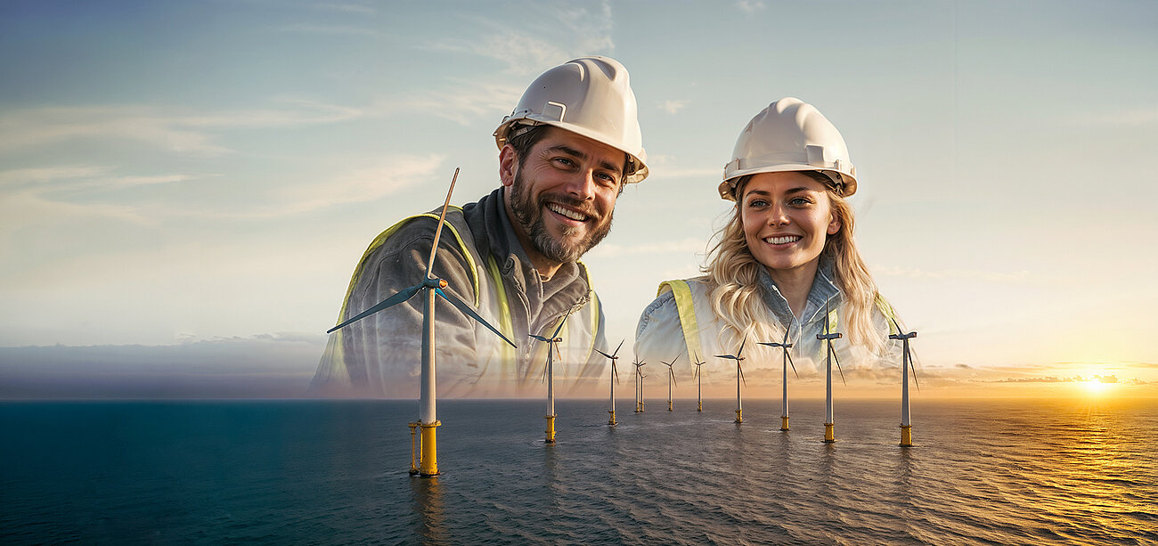 Two wind turbine technicians wearing safety helmets and high-visibility vests smile and pose together. Behind them, several large white wind turbines float on calm ocean water in a sunset-lit environment.