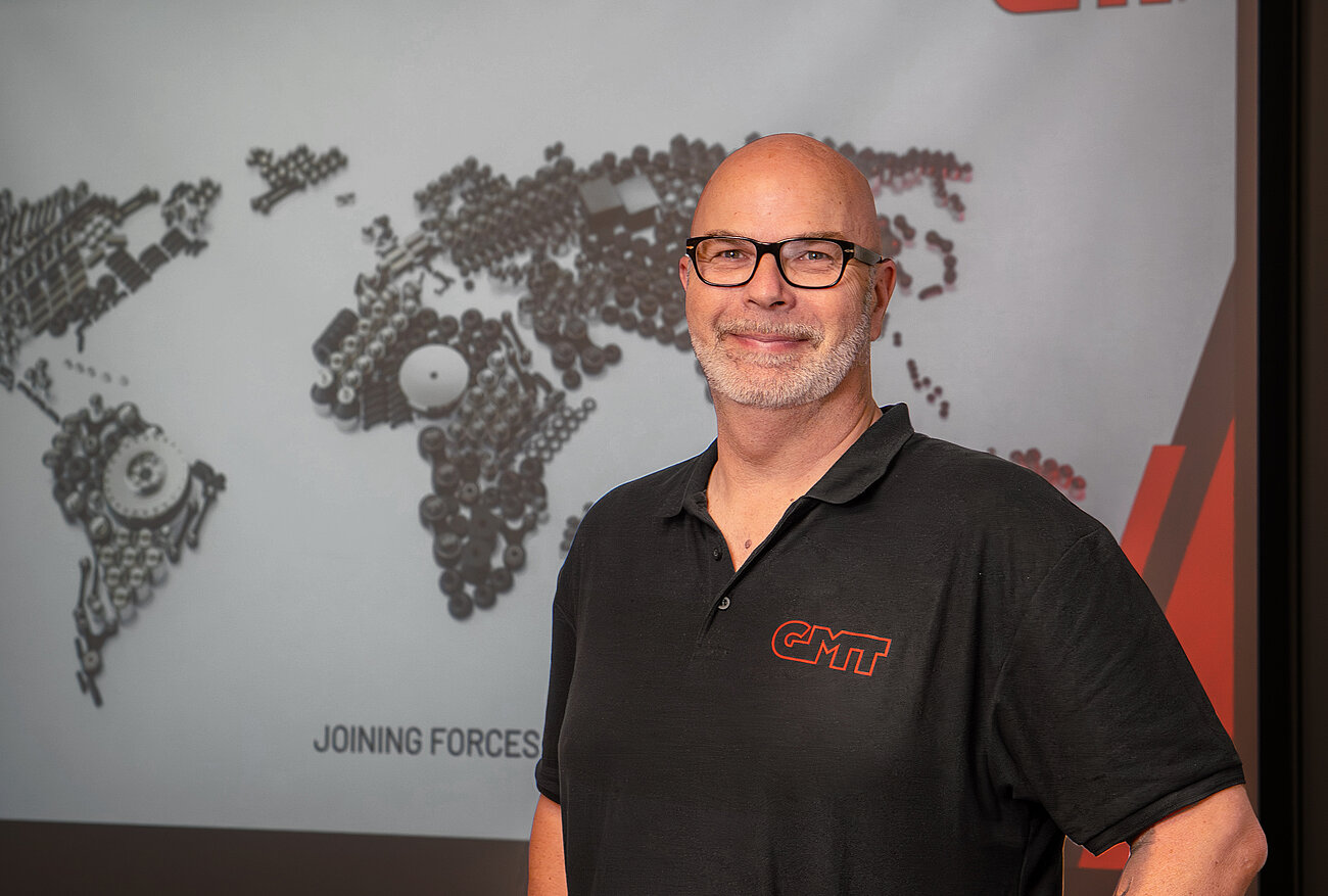 Person vor einer Wandgrafik mit Weltkarte im Unternehmensgebäude.