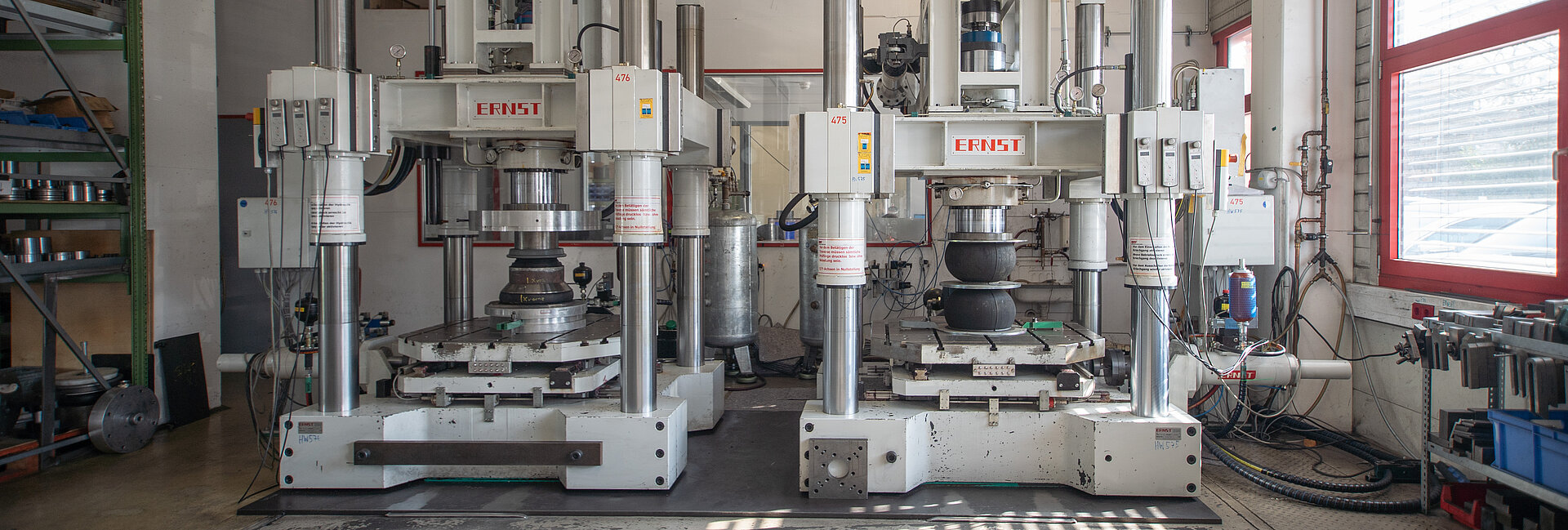 Two large industrial punching or metal pressing machines labeled with Hille branding are positioned side by side inside a factory setting, likely used for pressing, stamping, or forming metal sheets.